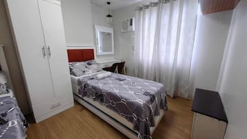Un dormitorio con cama, armario y un pequeño escritorio.