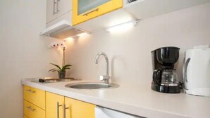 A kitchen with a sink, a coffee maker, and yellow cabinets. - Two bedroom apartment for 3 person (Jadranovo)