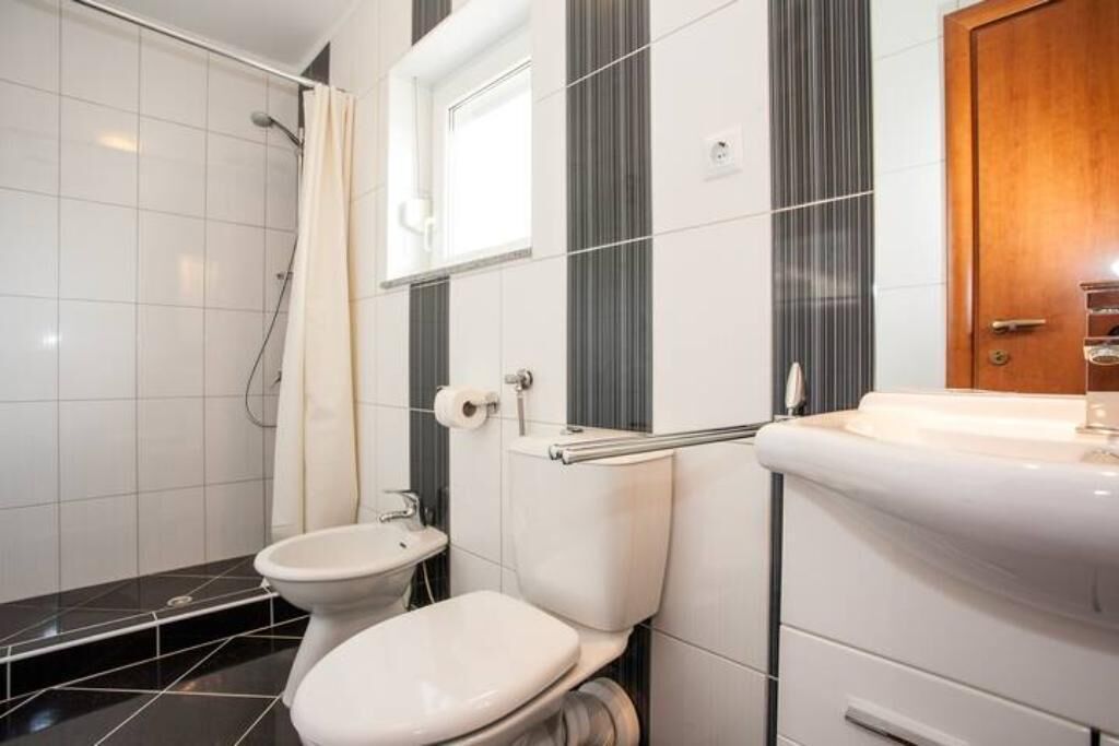 A bathroom with a toilet, sink, and shower.