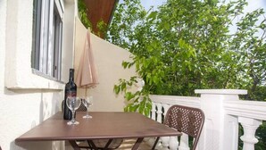 A table with a bottle and glasses, a chair, and a white balustrade.