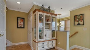 A hallway with a white cabinet, a chandelier, and a framed picture on the wall.