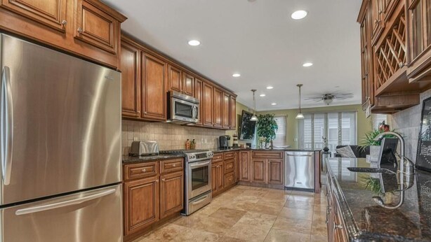 A modern kitchen with stainless steel appliances, wooden cabinets, and a large island.