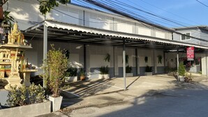 A covered outdoor area with a white building, potted plants, and a decorative structure. - SS GUESTHOUSE (Bang Phli)