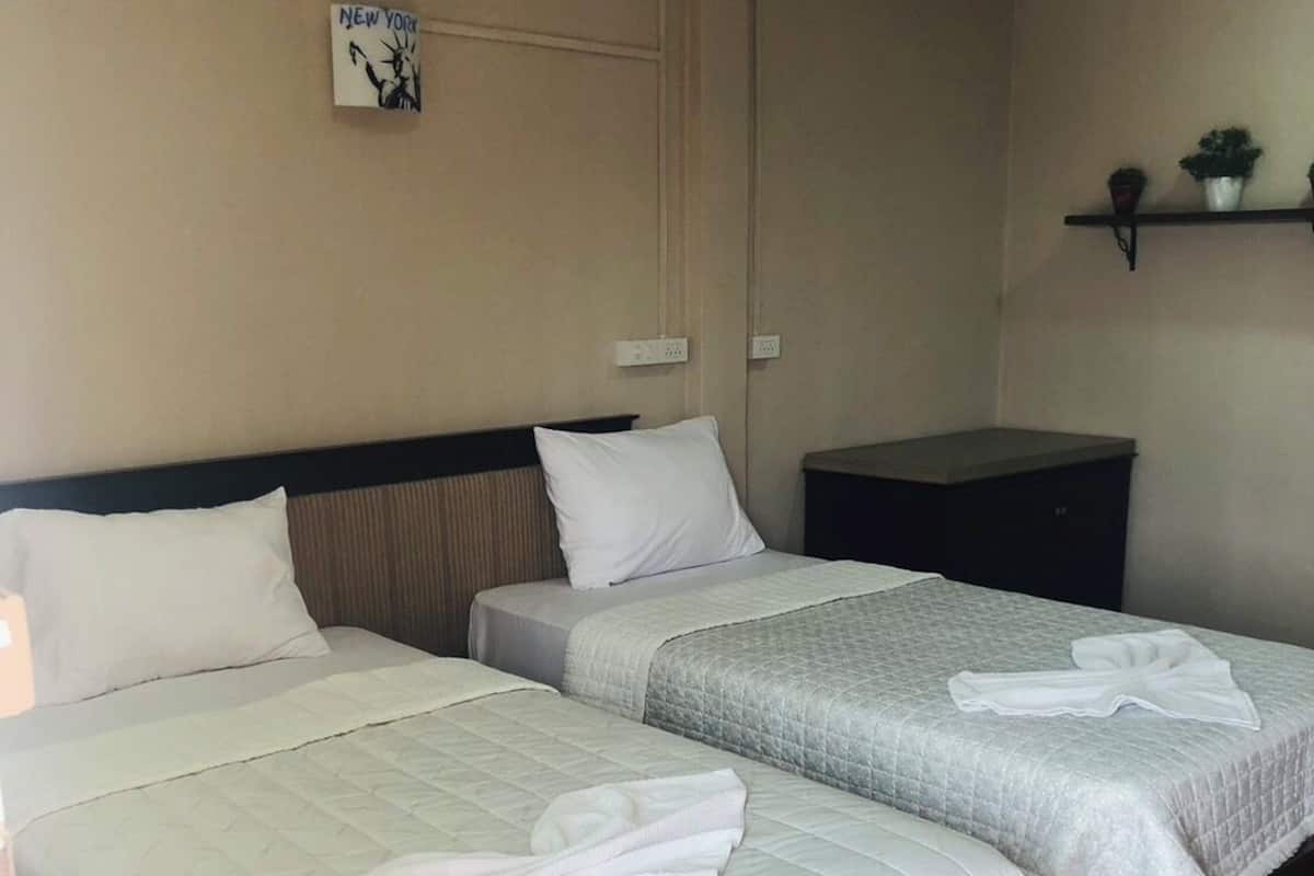 A hotel room with two beds, a nightstand, a wall clock, and a shelf with decorative items.