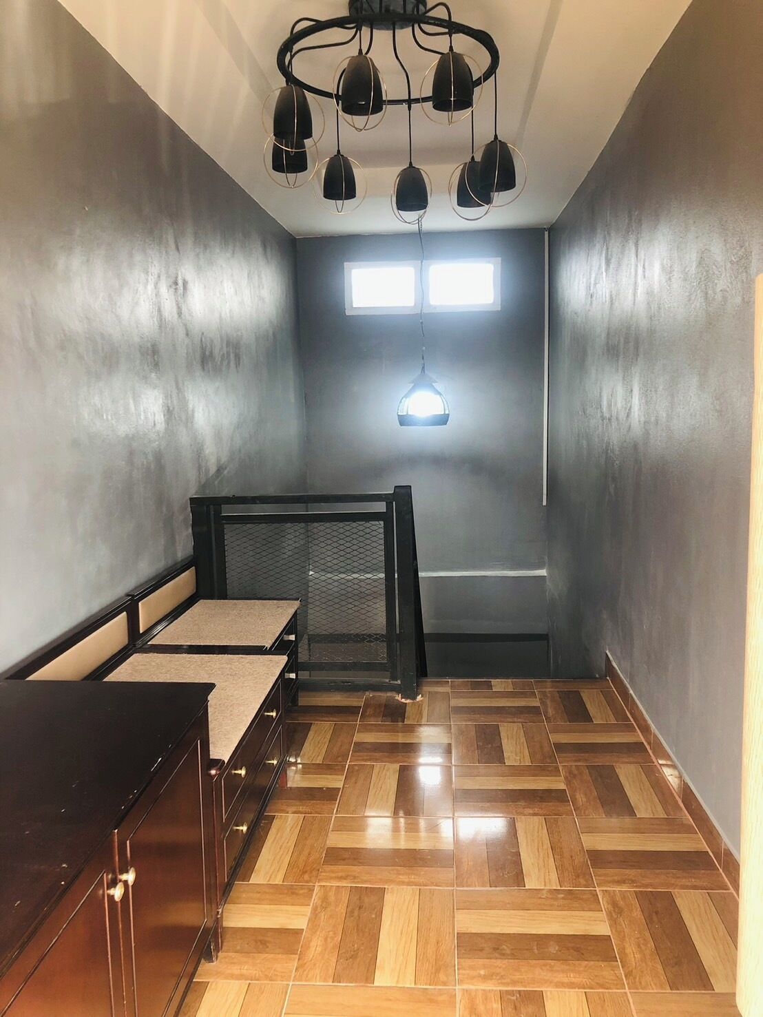 A room with a bed, a desk, and a hanging light fixture.