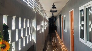 A narrow hallway with a patterned floor, a decorative wall, and a hanging light fixture. - SS GUESTHOUSE (Bang Phli)