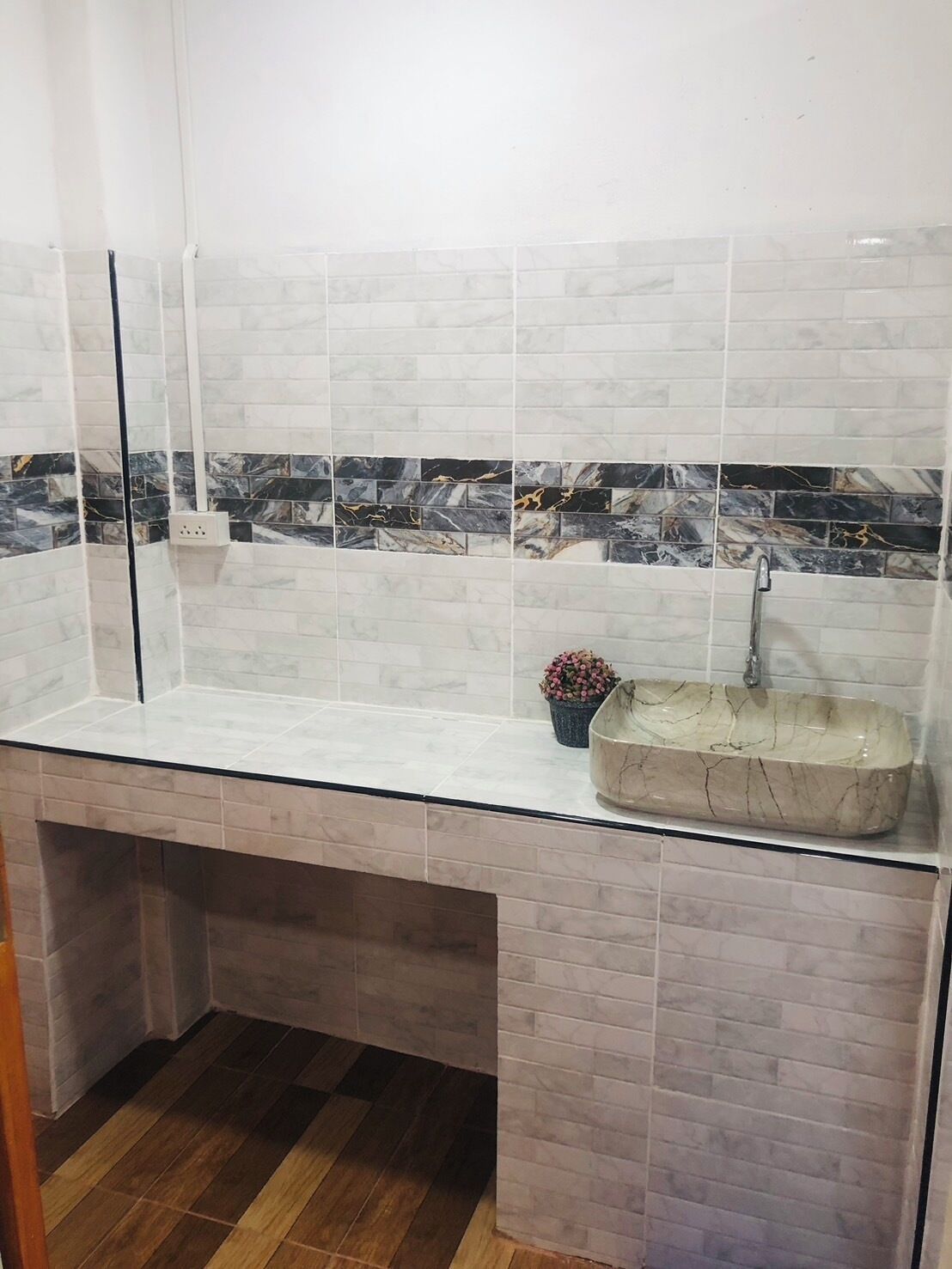 Un baño con lavamanos de mármol, un espejo y una planta en maceta.
