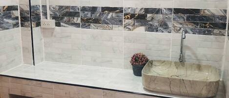 Un baño con lavamanos de mármol, un espejo y una planta en maceta.