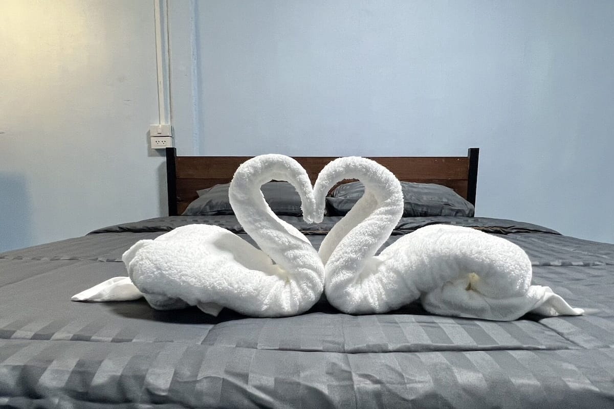 A bed with a grey bedspread and a wooden headboard.