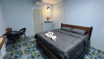 A bedroom with a bed, a desk, a chair, a door, and a wall-mounted air conditioner.