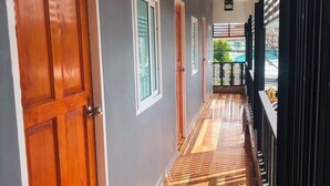 A hallway with wooden doors and windows, a patterned floor, and a balcony with a railing. - SS GUESTHOUSE (Bang Phli)