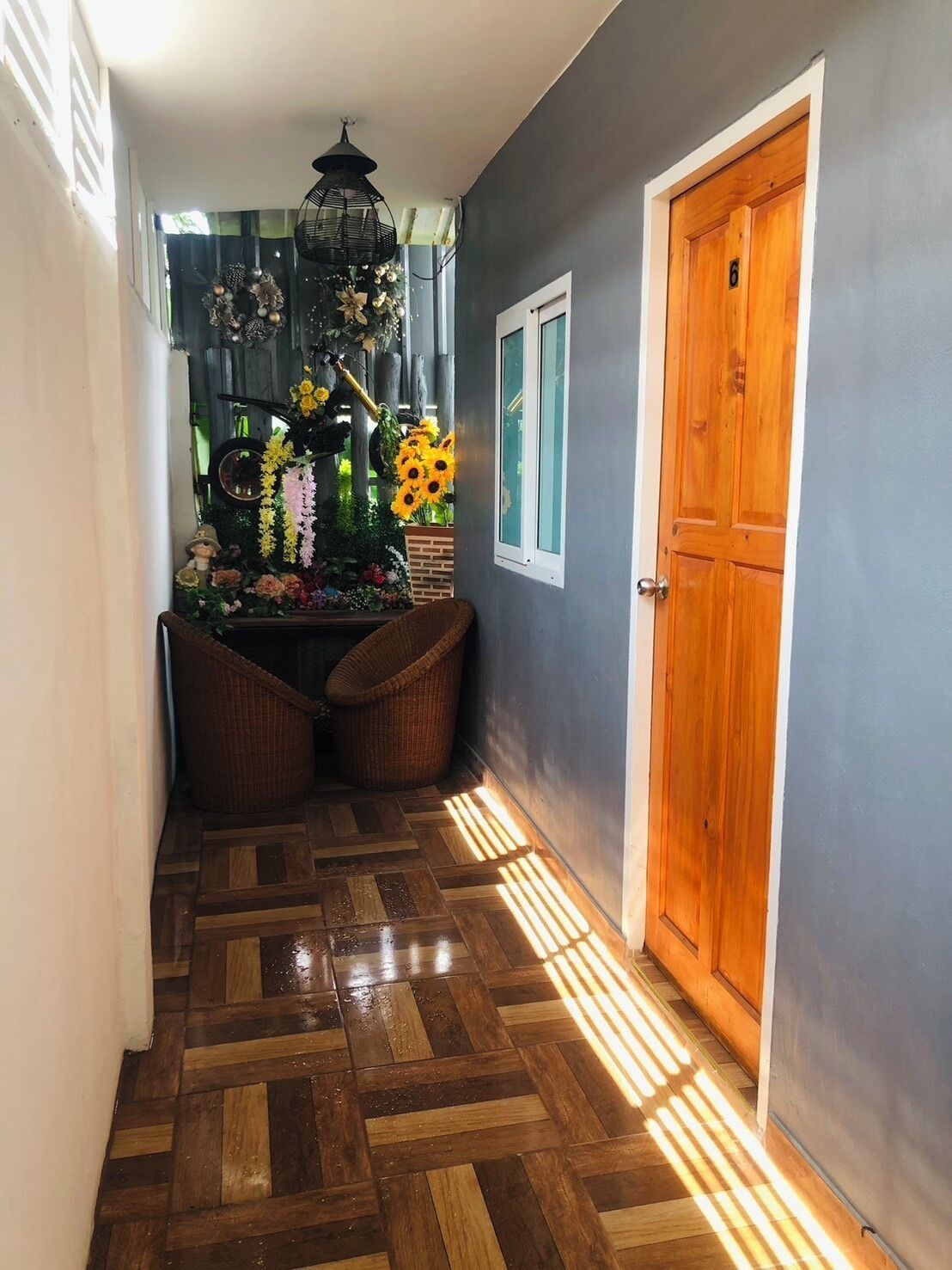 A hallway with a wooden floor, a wooden door, and a window.