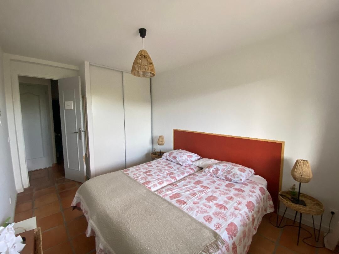Een slaapkamer met een bed, een bedlampje en een deur naar een andere kamer.