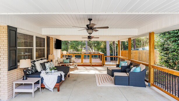 A covered porch with a ceiling fan, outdoor seating, and a view of the backyard.