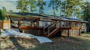 A two-story house with a covered porch, a wooden deck, and a ramp leading to the entrance.