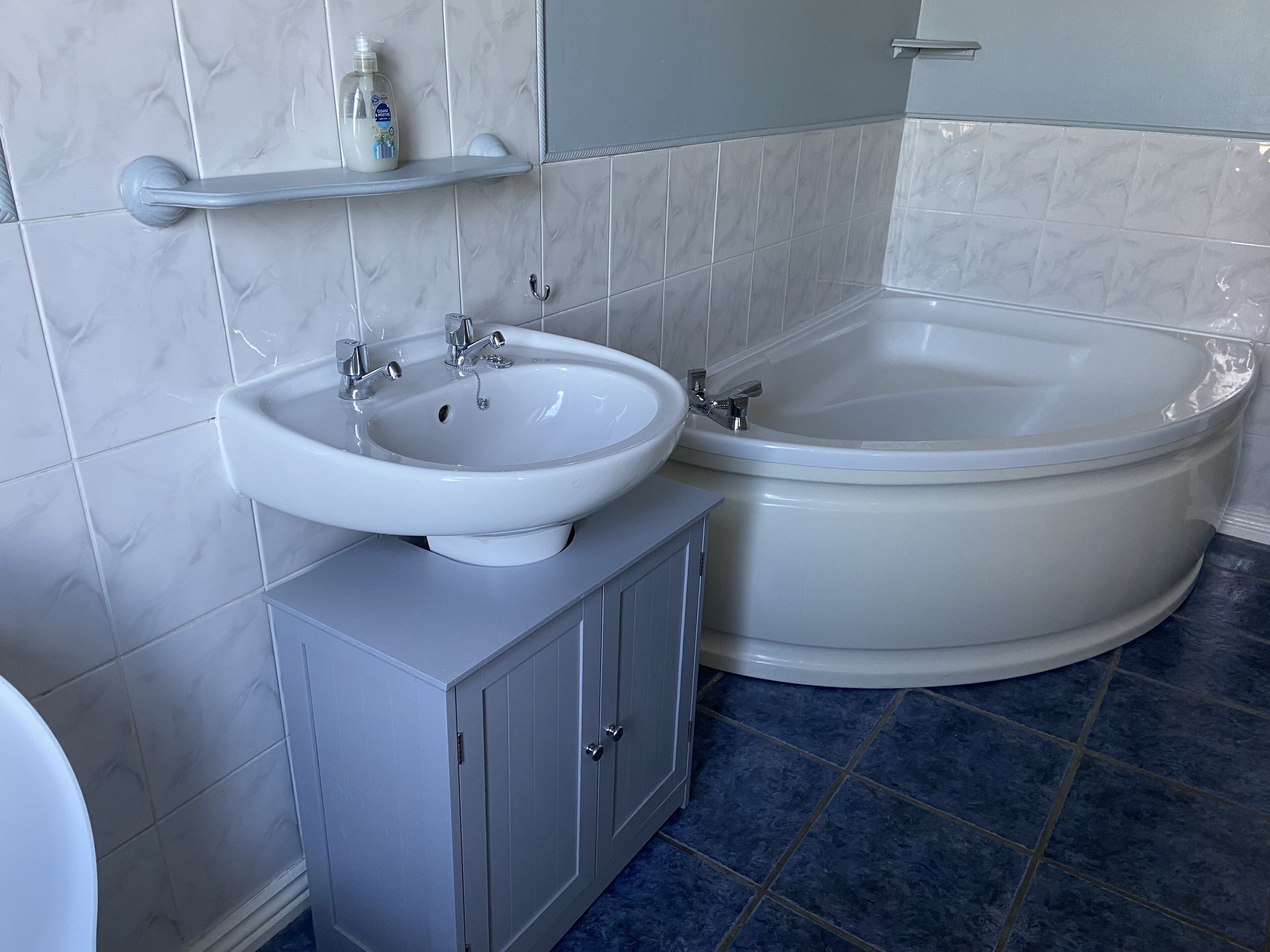 A bathroom with a white sink, a bathtub, and a cabinet.