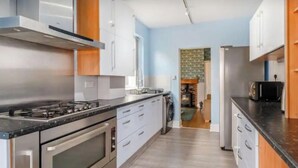 Eine moderne Küche mit Edelstahlgeräten, weißen Schränken und einer Holz Arbeitsplatte.