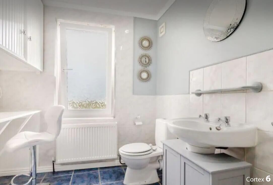 A bathroom with a toilet, a sink, a mirror, and a window.