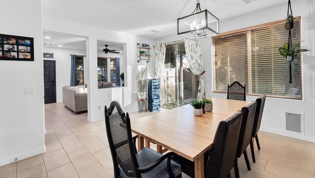 A modern dining area with a wooden table and chairs, a hanging light fixture, and a view through a glass door to a living space. - Cuban inspired Mid Term Rental in the heart of Gilbert  (Gilbert)