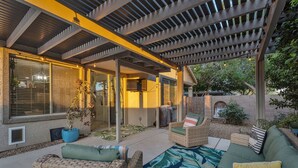 A covered patio area with wicker furniture, a large potted plant, and a view of the house. - Cuban inspired Mid Term Rental in the heart of Gilbert  (Gilbert)