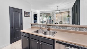 A modern kitchen with a double sink, dark cabinets, and a decorative backsplash. - Cuban inspired Mid Term Rental in the heart of Gilbert  (Gilbert)