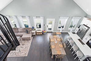 A spacious living area with a wooden dining table, a sofa, and a staircase.