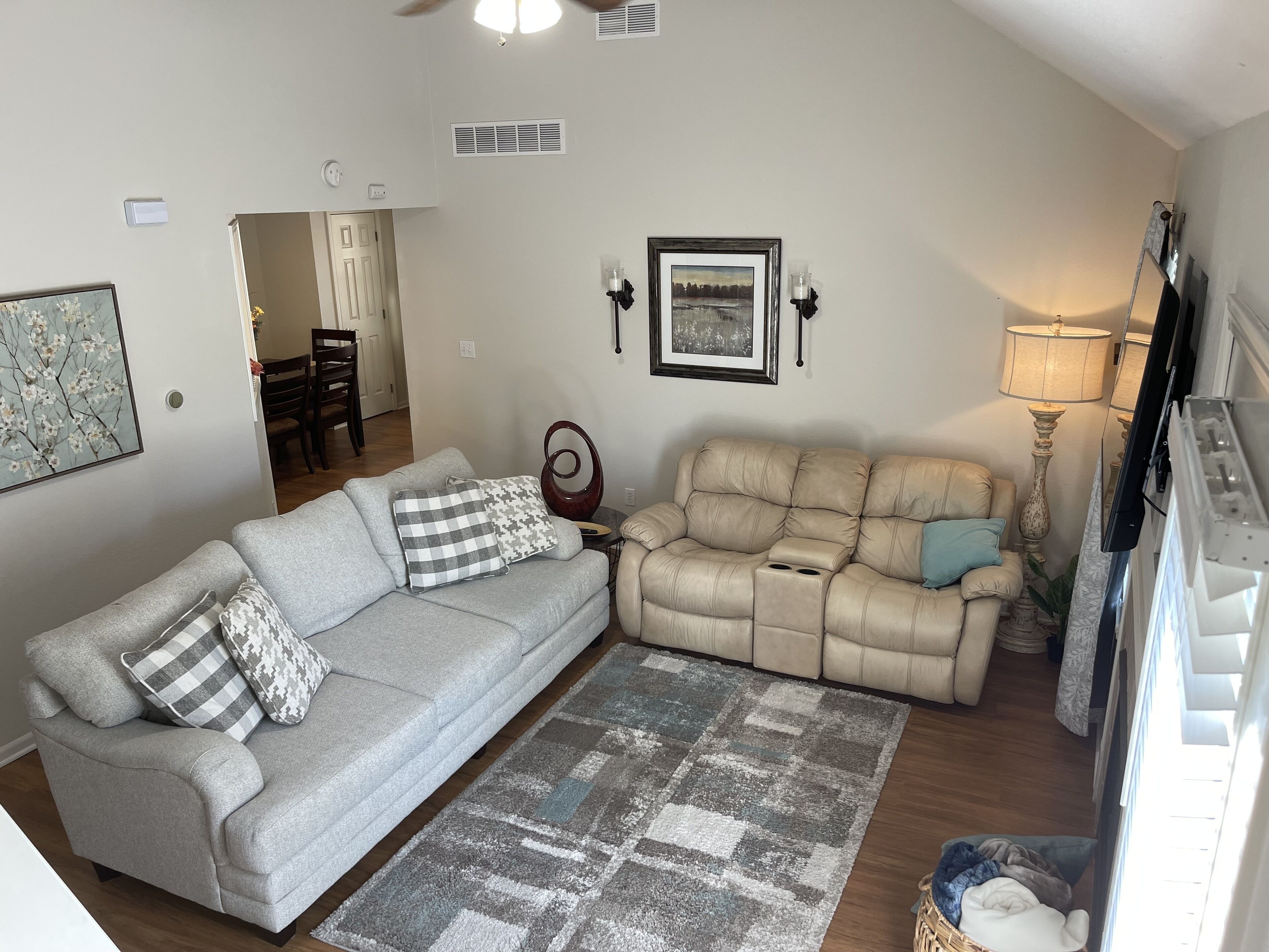 A living room with two sofas, a rug, a framed picture, and a lamp.
