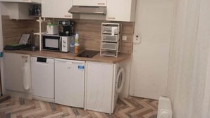Eine kleine Küche mit Mikrowelle, Kaffeemaschine und kleinem Kühlschrank.