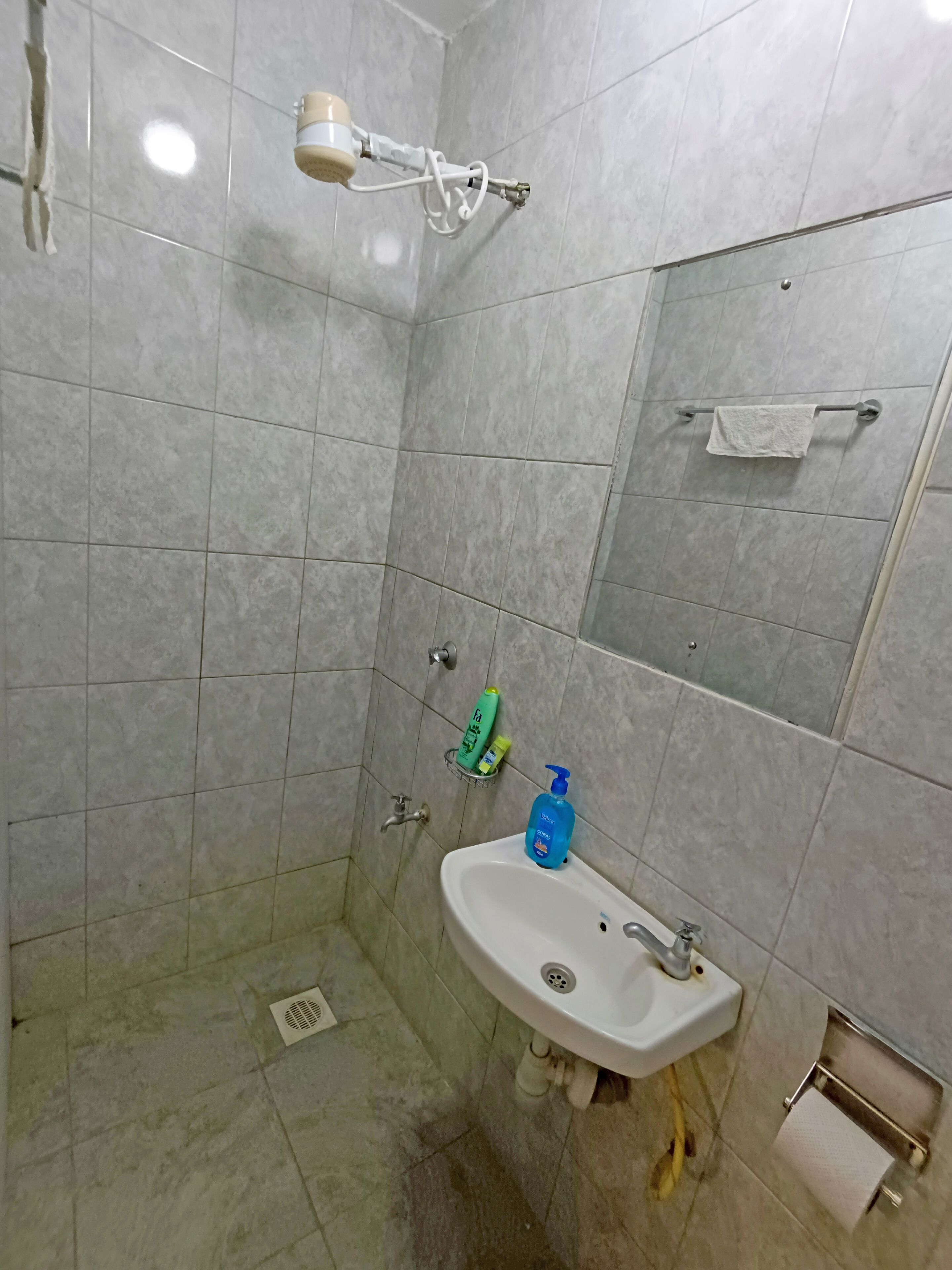 A bathroom with a sink, mirror, towel rack, and shower.