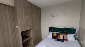 A bedroom with a bed, a wardrobe, and a wall-mounted light fixture. - Quiet Urban Stay with Views, 0742 for 616 then 120 (Nairobi)