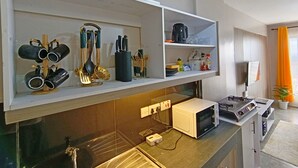 A kitchen with a microwave, stove, and utensils on shelves. - Quiet Urban Stay with Views, 0742 for 616 then 120 (Nairobi)