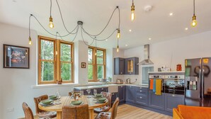 Een moderne keuken met donkere kastjes, een centraal eiland en een eetgedeelte met leren stoelen.