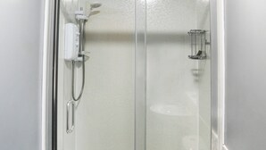 Un bany amb una cabina de dutxa de vidre, un lavabo blanc i un escurapulides.