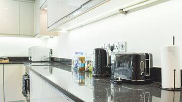 A modern kitchen with a black countertop, stainless steel appliances, and a white backsplash.