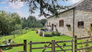 A stone building with a grassy yard and a wooden gate. - Slade Barn - UK42977 (Brayford)