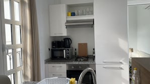 A compact kitchen with a microwave, coffee maker, and a cutting board. - La Perle à Marsa Plage (La Marsa)