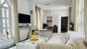 A modern living room with a sofa, coffee table, and TV. There is a kitchen area visible through an open door. - La Perle à Marsa Plage (La Marsa)