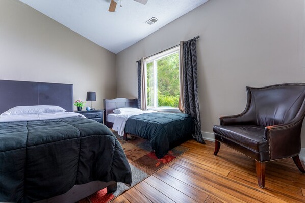Une chambre avec deux lits, une chaise, une table de chevet et une fenêtre avec des rideaux.