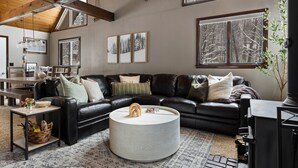 A cozy living room with a black leather sofa, a round coffee table, and a fireplace. - Shanty Creek Escape l Ski l Hot Tub l Pool (Bellaire)