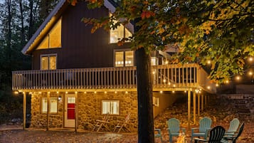 A stone building with a wooden deck, outdoor seating, and a fire pit.