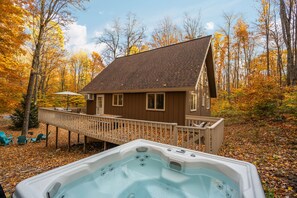 Une cabane avec un bain à remous, une terrasse et un paysage automnal aux couleurs flamboyantes.