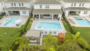 A residential complex with multiple swimming pools, a covered patio area, and a small wooden structure. - House Resort at Encore Reunion - Disney (Kissimmee)