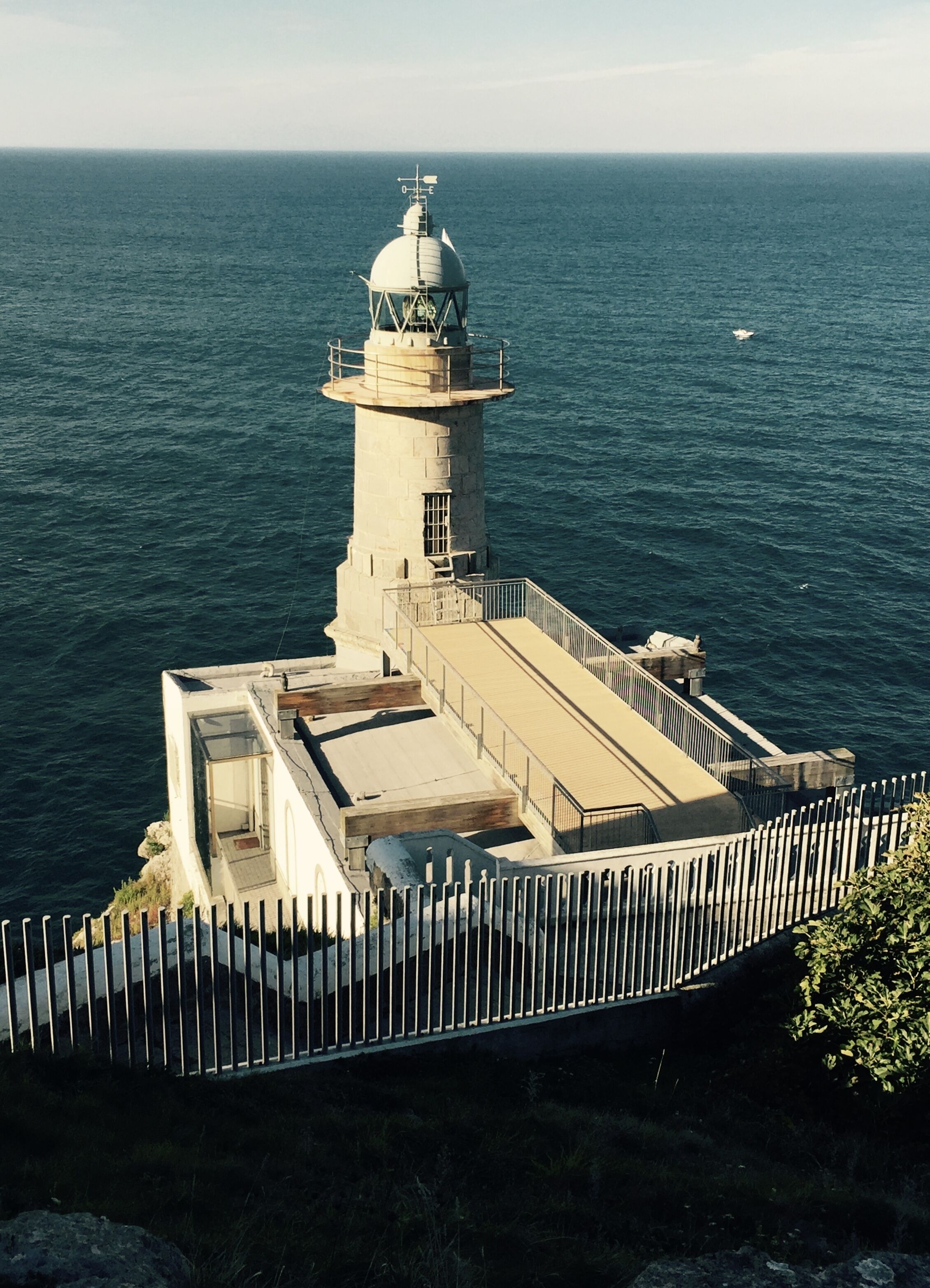 Un faro con una plataforma de observación y una zona vallada.