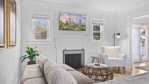 A living room with a sofa, a round coffee table, a chair, a fireplace, and a painting on the wall.