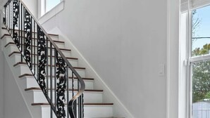A staircase with white walls and wooden steps, leading to a landing with a window.