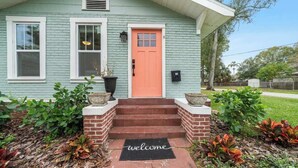 A house with a red door, white windows, and a welcome mat in front.