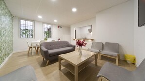 A modern living room with a grey sofa, a wooden coffee table, and a dining area with a white table and chairs. - VIZCAINOS GARDEN (Segovia)