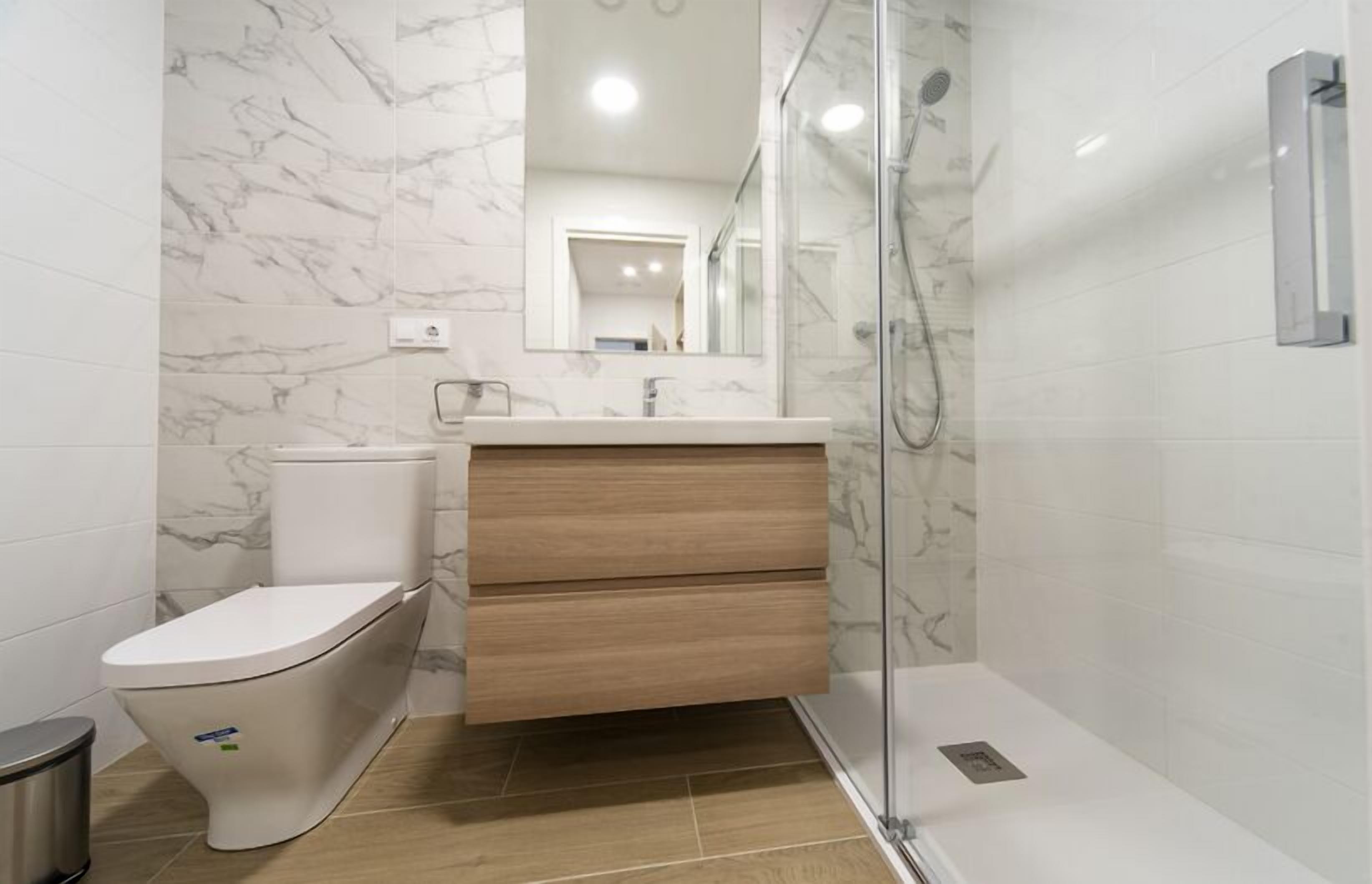 Een moderne badkamer met toilet, wastafel en douche.