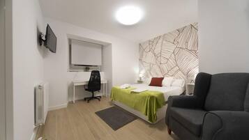 A modern bedroom with a bed, a desk, a chair, and a sofa.