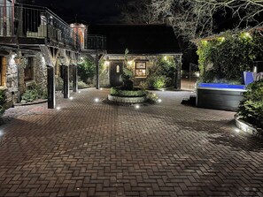A brick-paved courtyard with a central fountain, surrounded by stone walls and greenery.